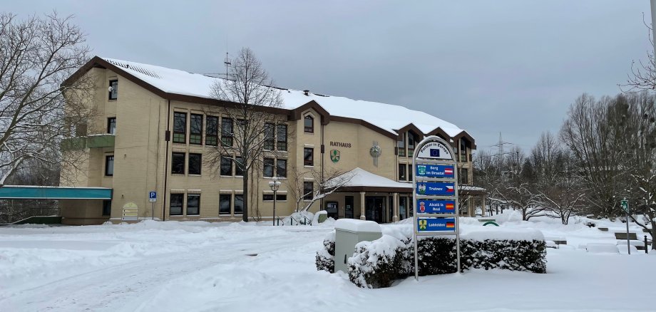 Das Rathaus und der Rathausvorplatz mit dem Brunnen Lohfelden sind schneebedeckt. Im Vordergrund ist das Partnerschaftsschild Berg im Drautal+Trutnov+Alcalá la Real.